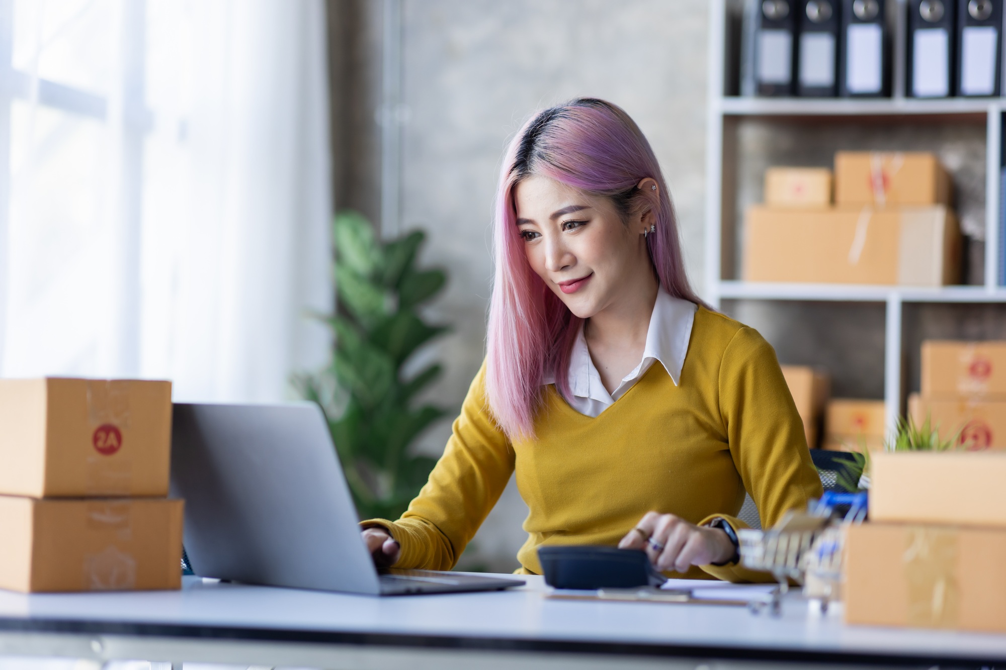Startup SME small business entrepreneur of freelance Asian woman wearing apron using laptop and box