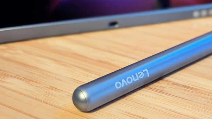 A close-up view of the Lenovo Tab Pen Plus stylus resting on a wooden surface, with a tablet partially visible in the background.
