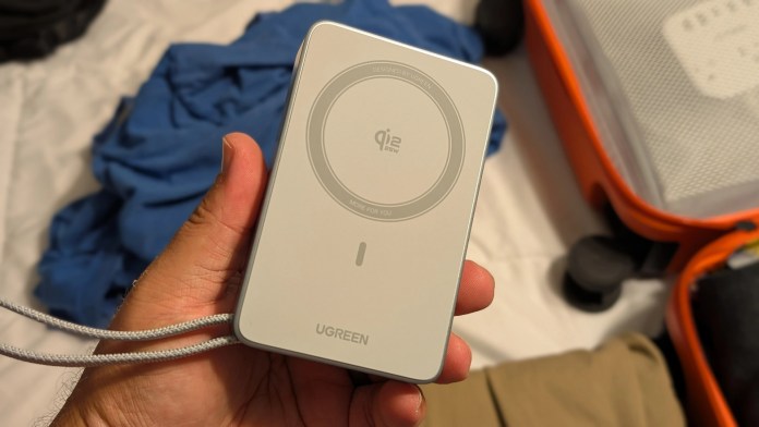 Hand holding the UGREEN MagFlow magnetic power bank, showcasing its Qi2 charging capabilities and compact design.