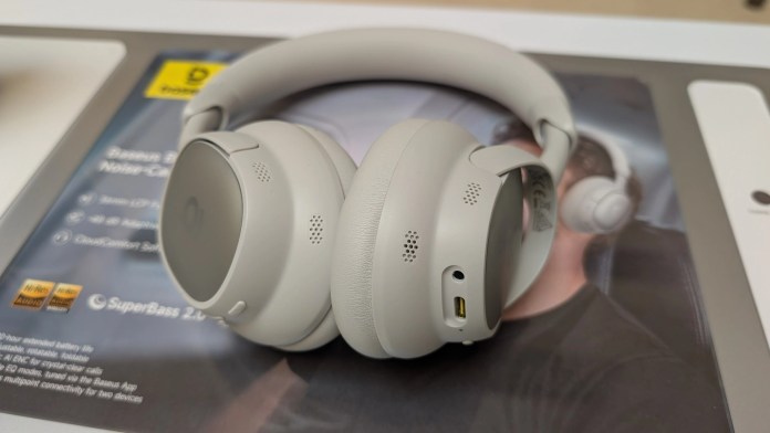 Close-up of Baseus Inspire XH1 noise-cancelling headphones displayed on a promotional background, showcasing the design and features.