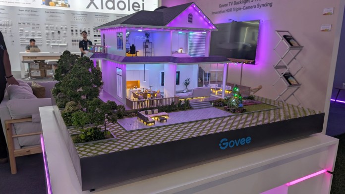 A miniature model of a smart home display featuring Govee lighting in various colors, showcasing modern design elements and outdoor landscaping.