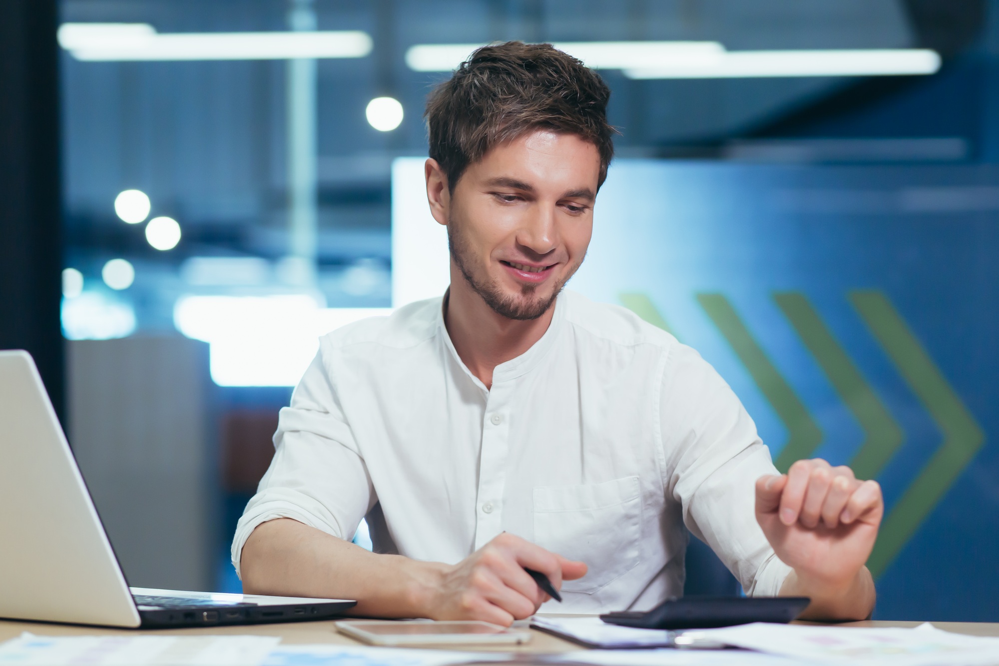 Young businessman counts on a calculator sums up the annual financial report.