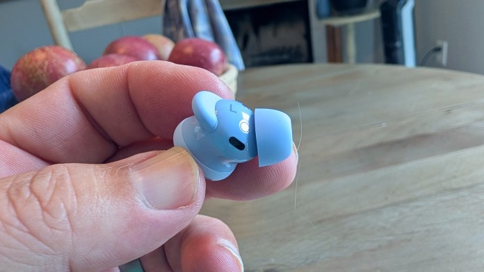 A person holding a blue Pixel Buds 2a earbud with a hand, featuring a close-up view of the earbud's design and color.