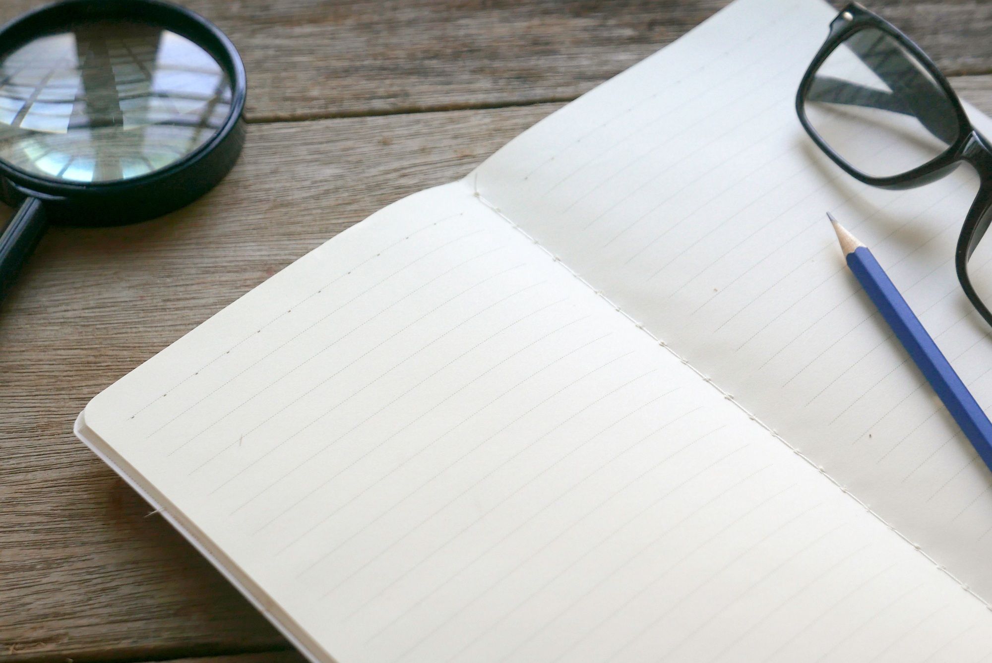 Notebook with stationery on wooden background. Copy space for text or logo.