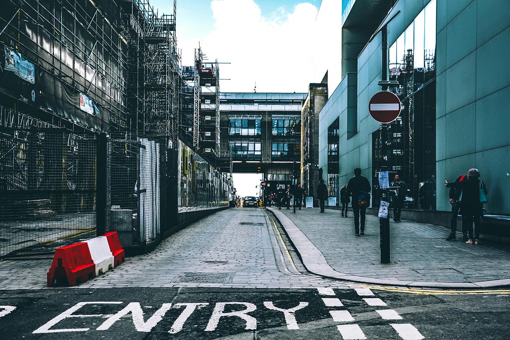 Building entrance hidden behind construction work (scaffolding) and confusing signage. Source: Pexels.